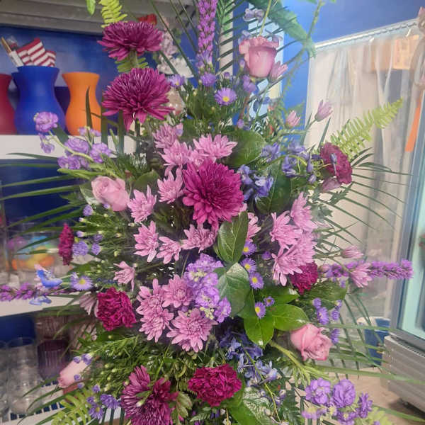 Tall bouquet of pink and purple flowers with palm fronds