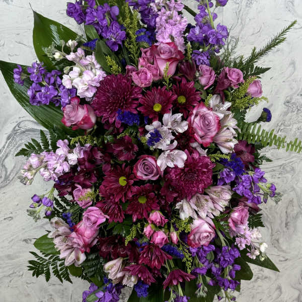 Large standing floral spray with pink and purple flowers on a black easel
