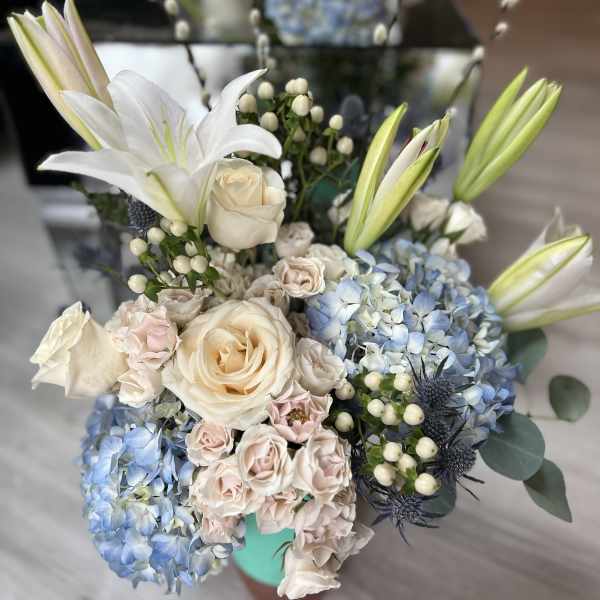 Bouquet of white lilies, cream roses, and blue hydrangeas