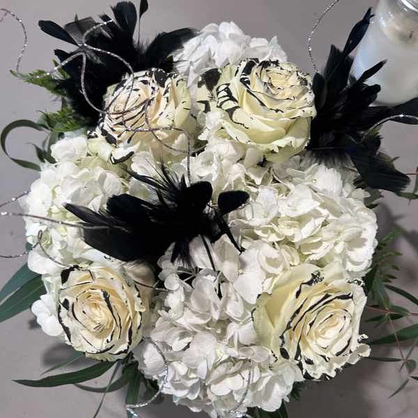 White hydrangea bouquet with cream roses and black feather accents