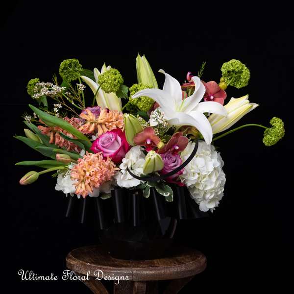 Mixed floral arrangement with white lilies, hydrangeas, and pink roses in a black container