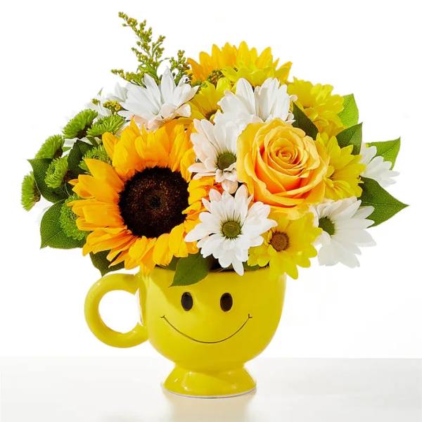 Yellow mug vase holding sunflowers, daisies, and a rose