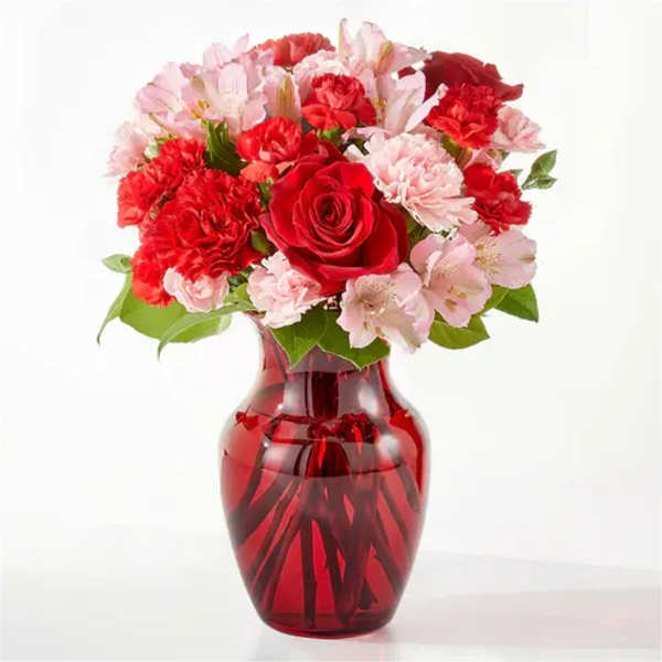 Red and pink flower bouquet in a red glass vase