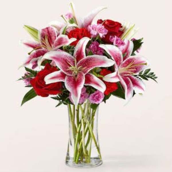 Bouquet of pink lilies and red roses in a clear glass vase