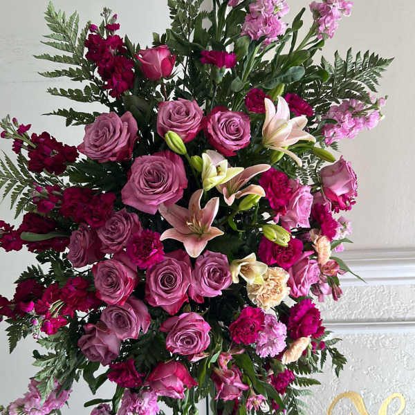Large pink and magenta floral standing spray on a black easel