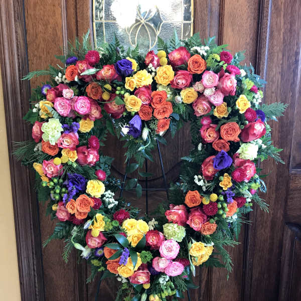 Heart-shaped floral wreath on a stand with multicolored roses