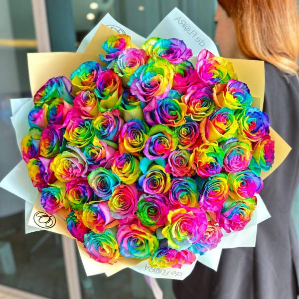 Bouquet of rainbow-colored roses wrapped in pale paper
