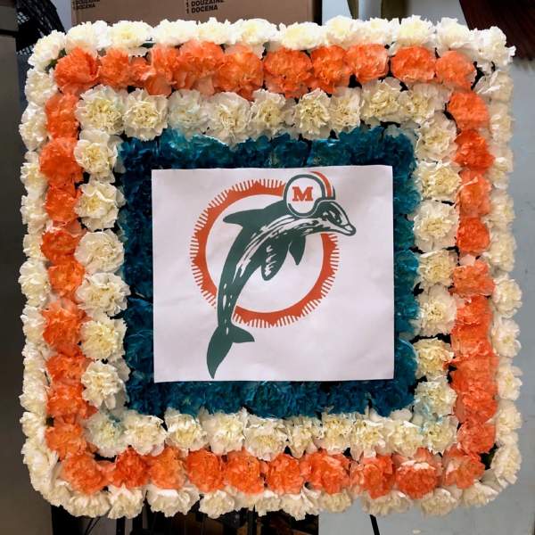 Square floral display with orange, white, and blue flowers around a logo