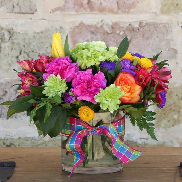 Colorful mixed bouquet in a glass vase with a plaid ribbon