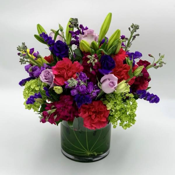 Colorful bouquet of lilies, roses, and carnations in a glass vase