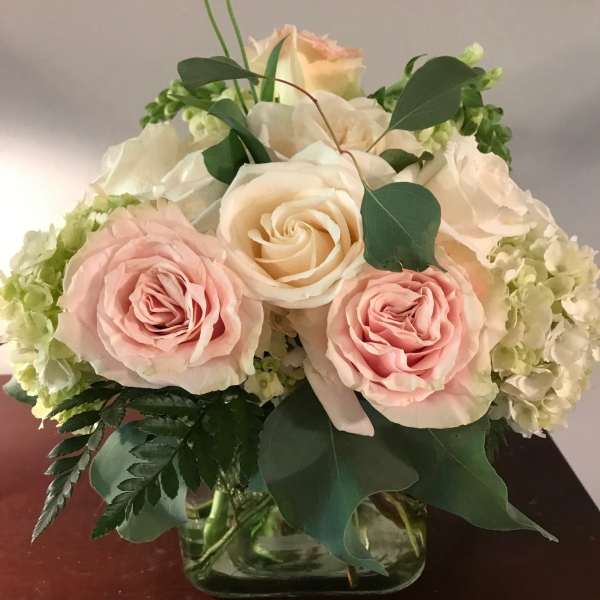Pink and cream roses arranged in a glass vase