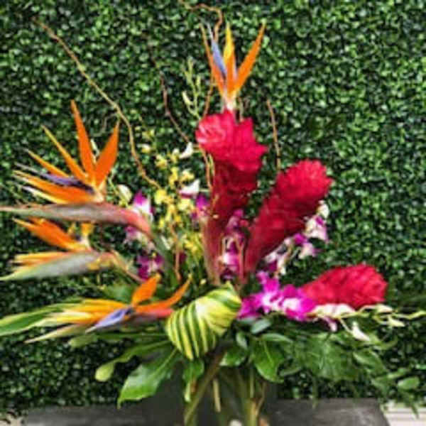 Tropical flower arrangement with bird of paradise and red blooms in a vase