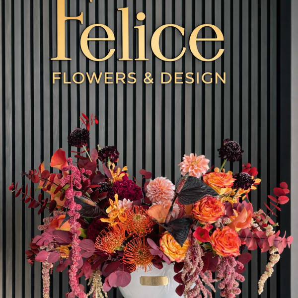 Large colorful floral arrangement in a white vase beneath a Felice Flowers & Design sign
