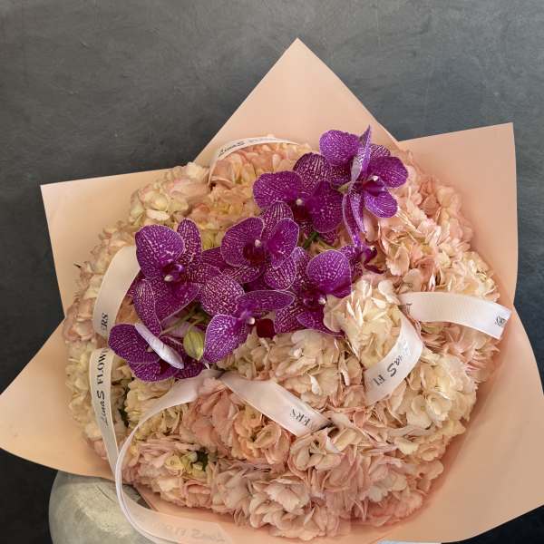 Pink hydrangea bouquet with purple orchids and ribbon accents