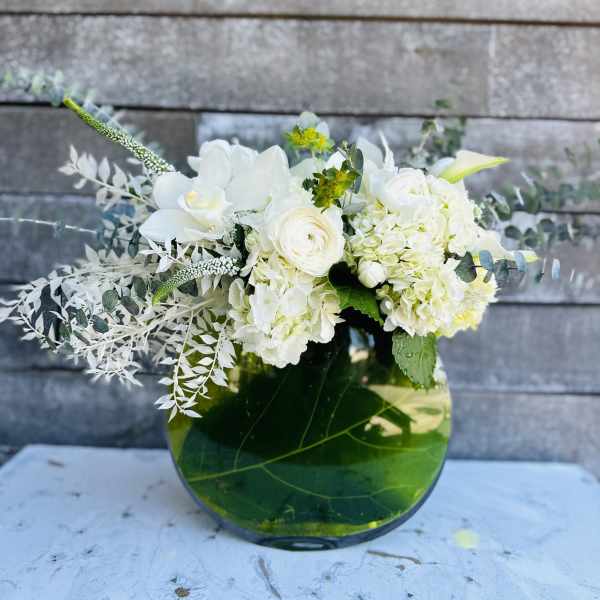 White floral arrangement in a green glass vase