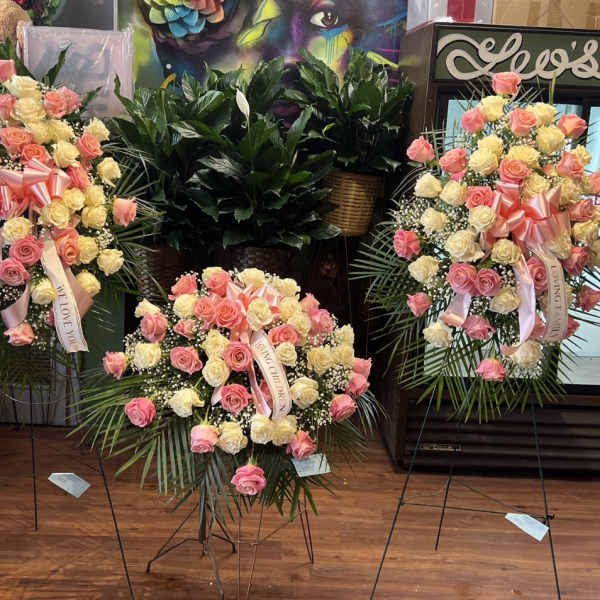 Three standing rose wreaths with pink and cream blooms and ribbons