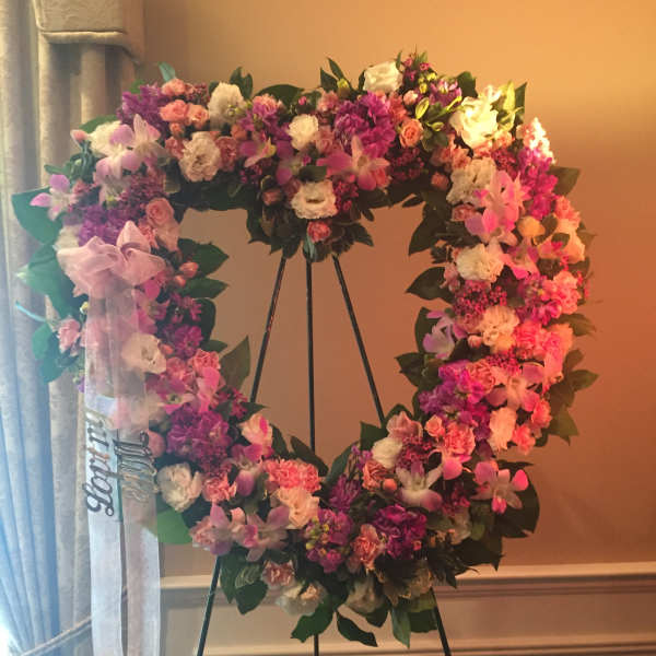 Heart-shaped floral wreath on an easel with a ribbon bow