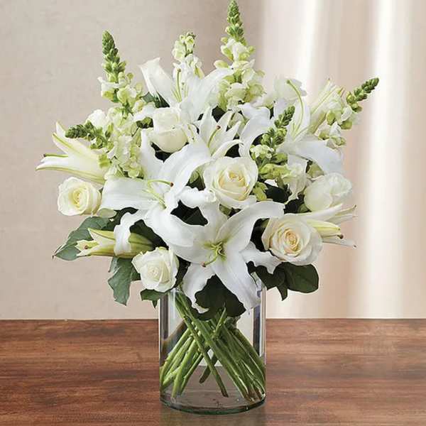 White lilies and roses arranged in a clear glass vase
