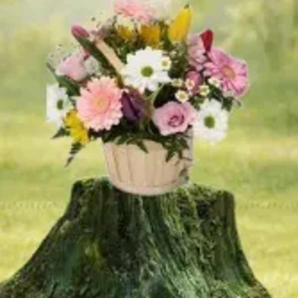 Pastel mixed flower basket with daisies, gerberas, and roses on a tree stump outdoors