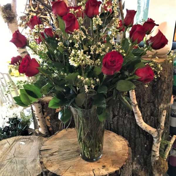 Red roses and white filler flowers in a clear glass vase