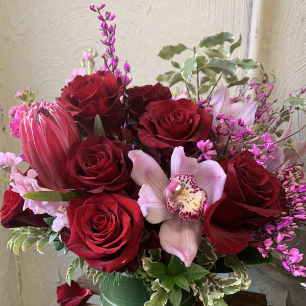 Red roses and a pale orchid in a green striped vase