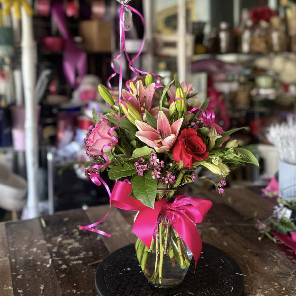 Birthday balloon above a pink and red flower bouquet in a glass vase