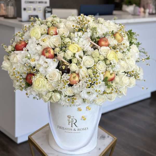 Large white floral arrangement with apples in a white hatbox