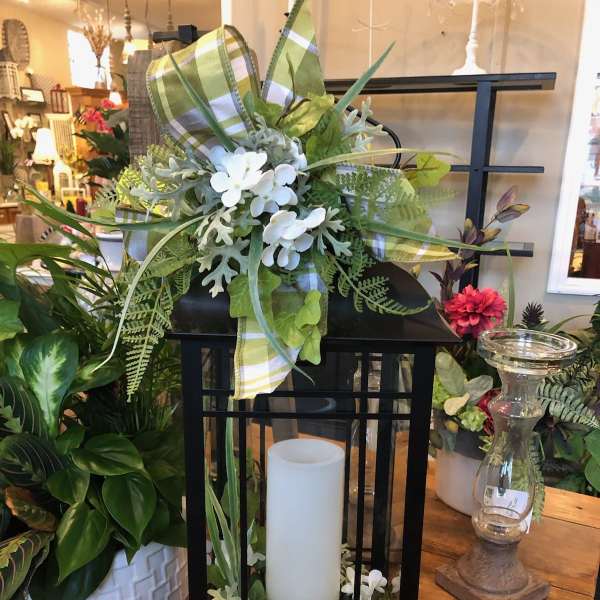 Black lantern with white candle and white floral accents
