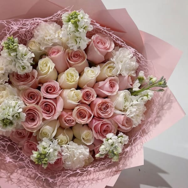 Bouquet of pink and white roses wrapped in pink paper