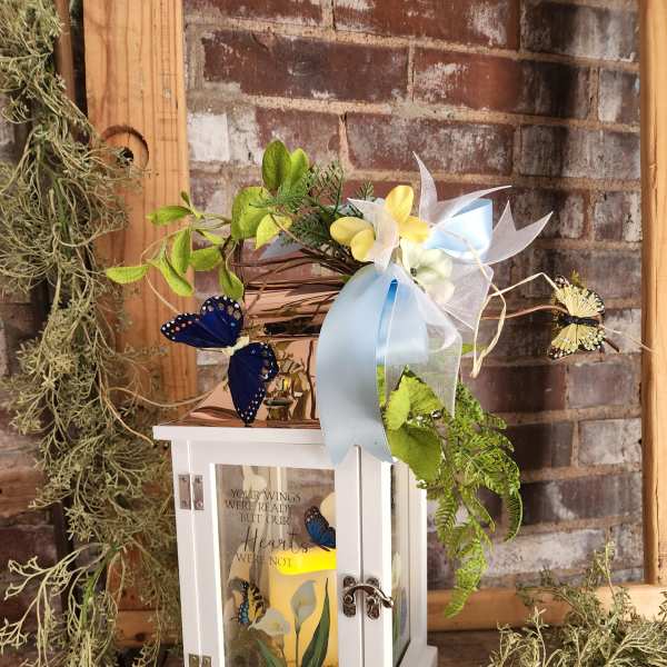 White lantern with butterflies, ribbon, and flowers on top