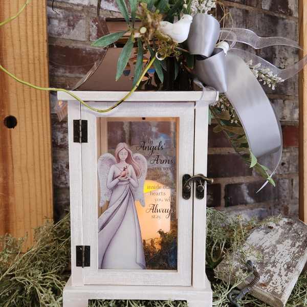 White memorial lantern with angel artwork and a small floral topper