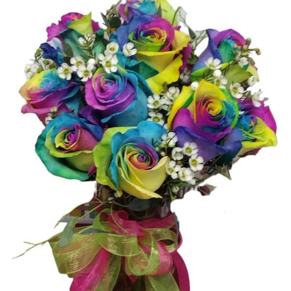 Rainbow-colored roses in a glass vase with small white filler flowers