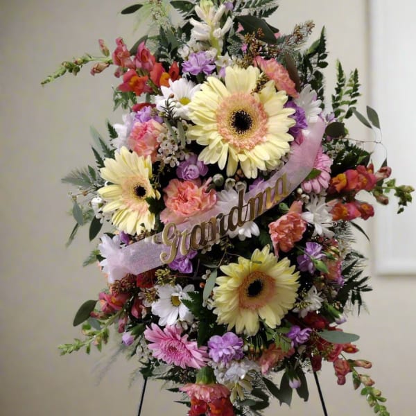 Standing floral spray with pastel flowers and a "Grandma" ribbon on an easel