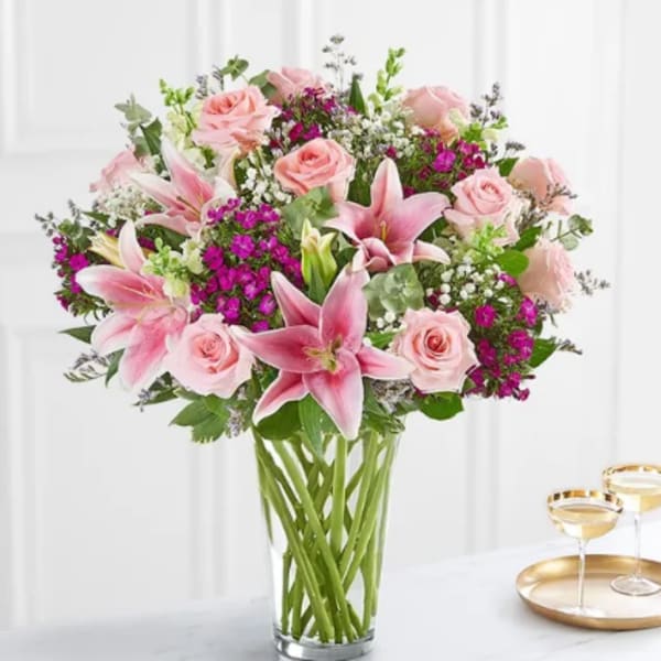 Pink lilies and roses arranged in a clear glass vase