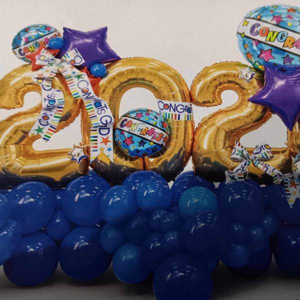 Gold 2024 balloons with blue and purple congratulatory balloons and a blue balloon base