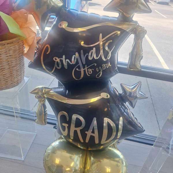 Black and gold graduation balloon display with star balloons and "Congrats to you GRAD!" text