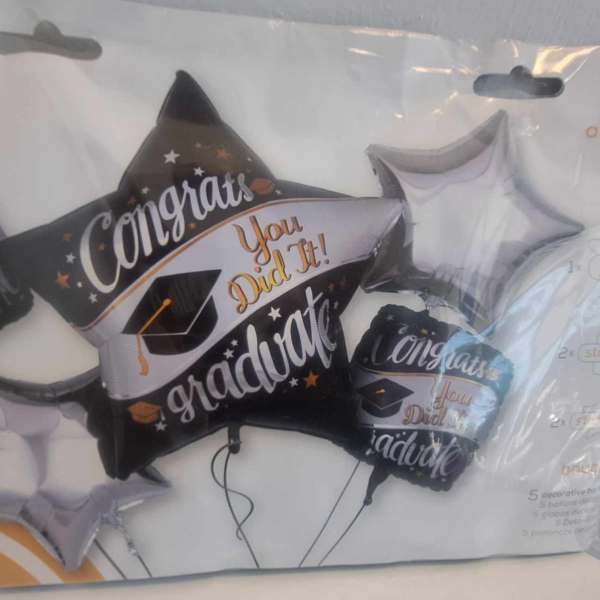 Graduation-themed foil balloons in black, white, and silver packaging