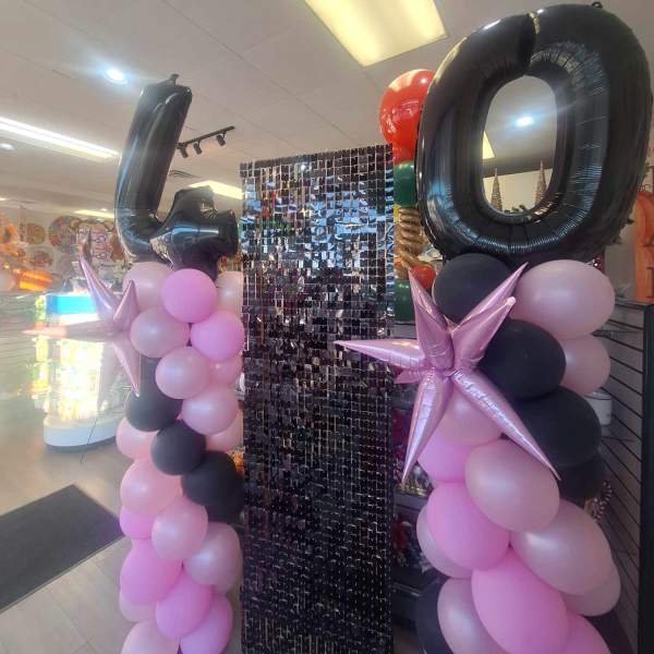 Balloon display with large black 40 numerals and pink, black, and lavender balloons