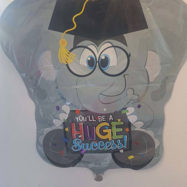 Graduation-themed balloon with a cartoon face and "You'll be a huge success" text