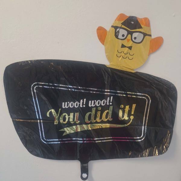 Black congratulatory balloon with a cartoon owl topper