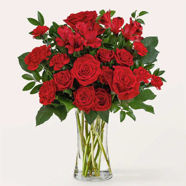 Red roses and carnations in a clear glass vase