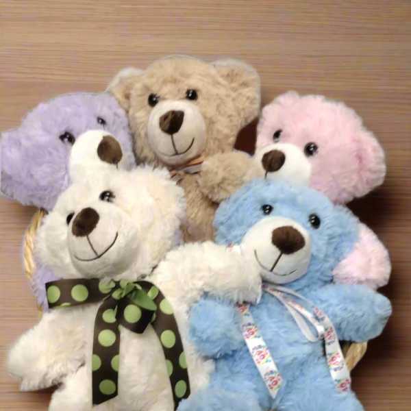 Five plush teddy bears in pastel colors arranged in a basket