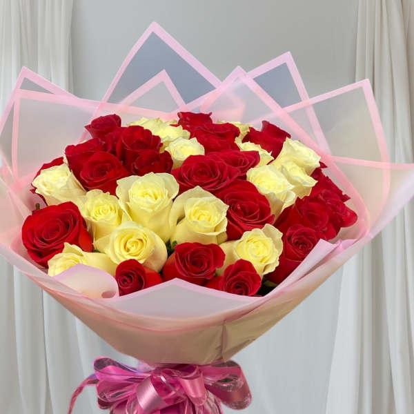 Bouquet of red and pale yellow roses wrapped in pink paper