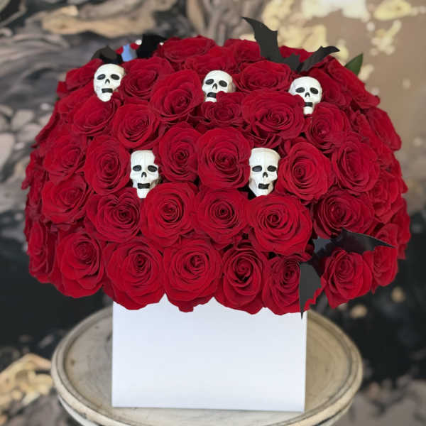 Red rose arrangement in a white box with small skull decorations