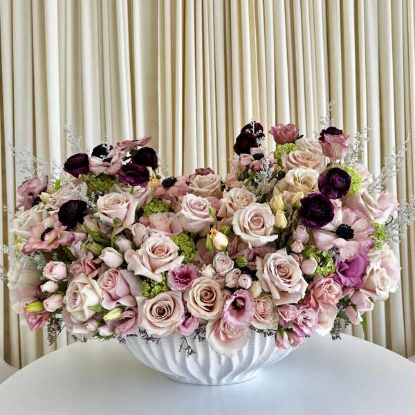 Low centerpiece of blush roses and mixed pink and white blooms in a white bowl