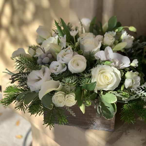 White floral arrangement in a wooden box with roses and calla lilies