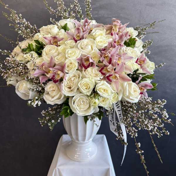 Large bouquet of white roses and pink orchids in a white vase