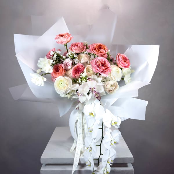 Pink and white bouquet with orchids and roses in a white vase