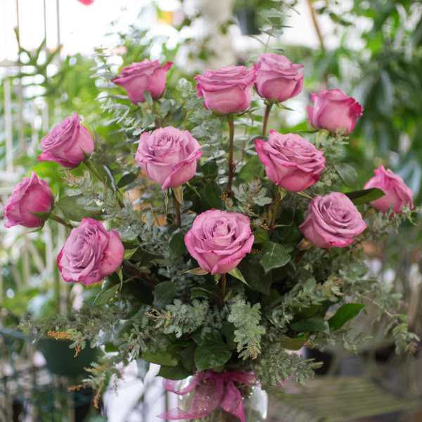 Pink roses arranged in a clear glass vase with greenery