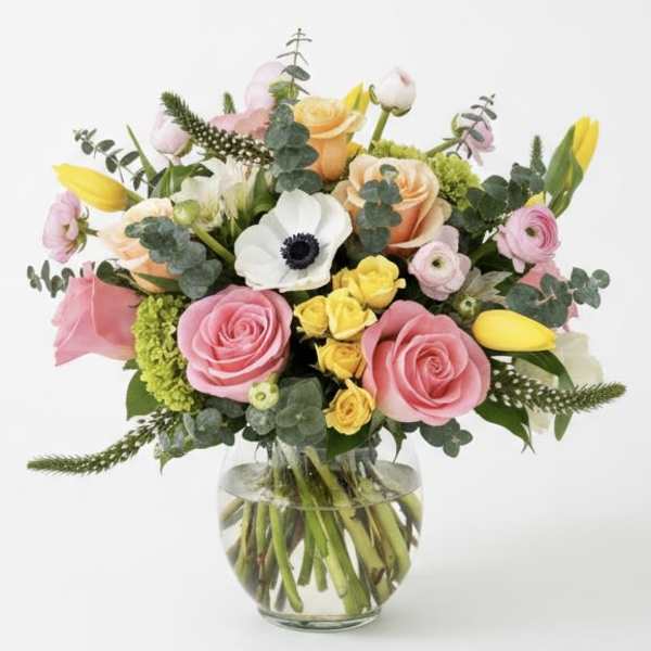 Mixed bouquet of pink and yellow flowers in a clear glass vase